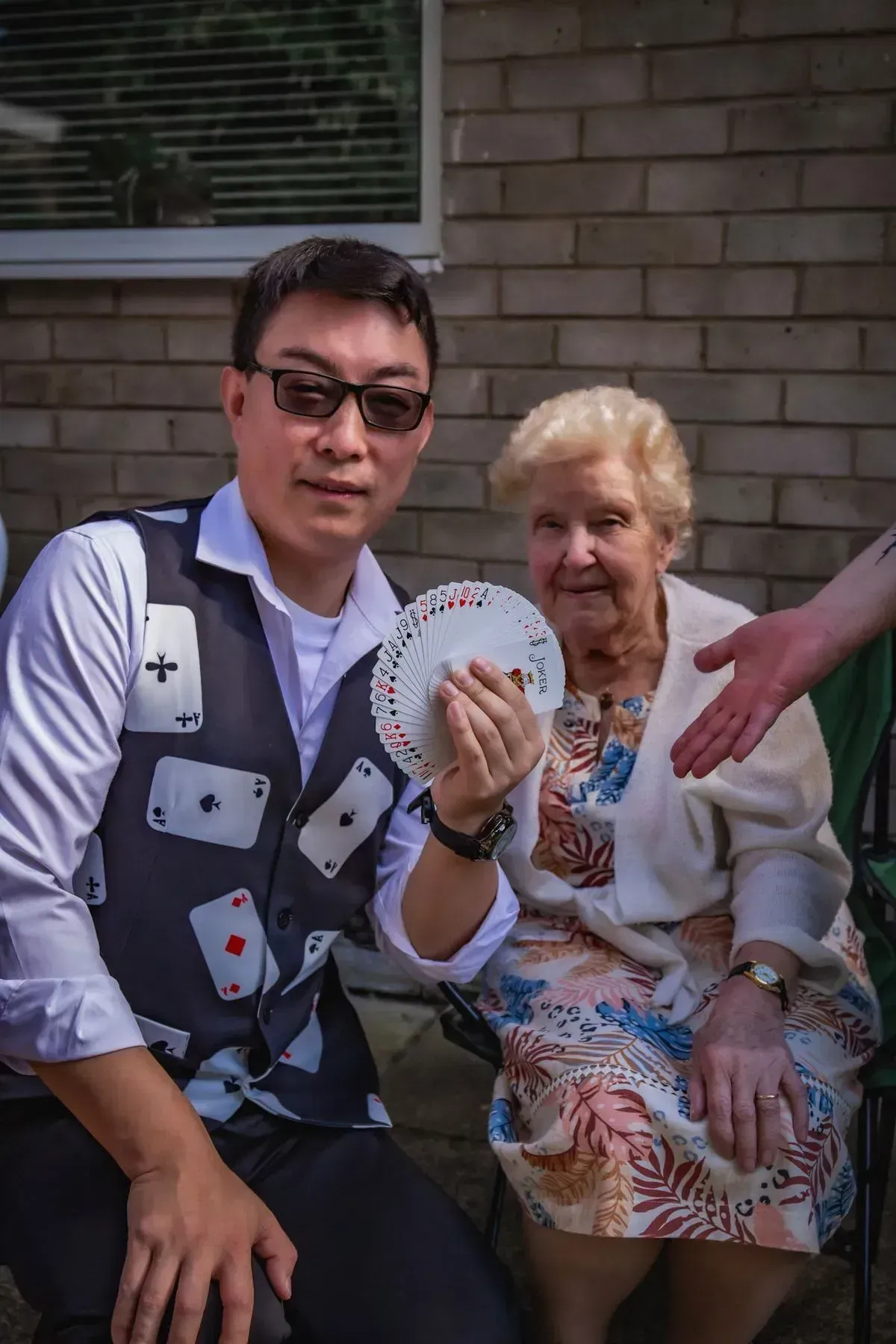 Magic Yin performing a card trick for an elderly resident at an outdoor community event